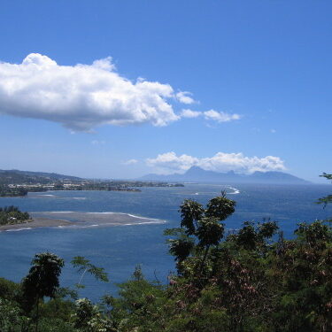 Coastal landscape with ocean and distant mountains.