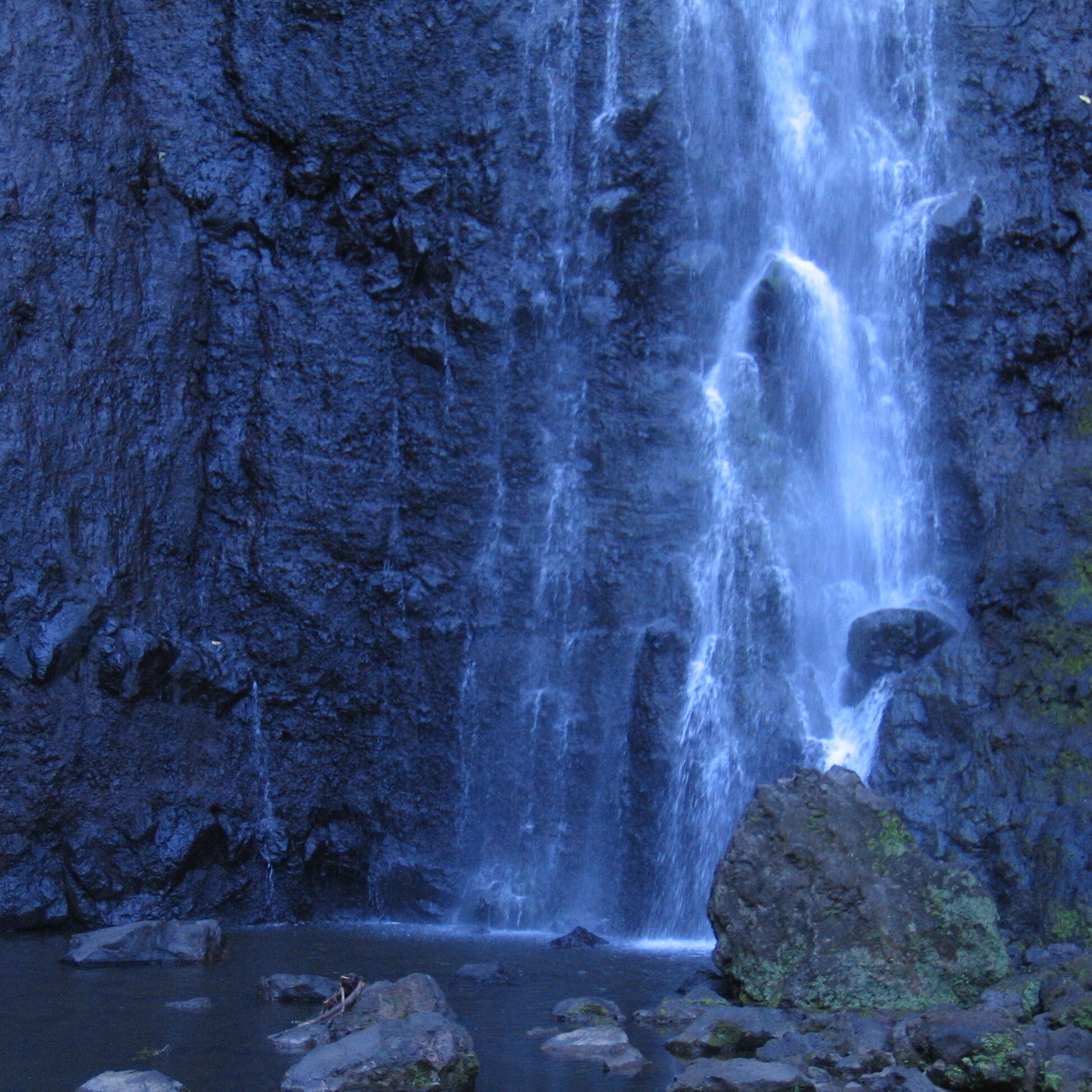 Waterfall cascading over dark rocky cliff.