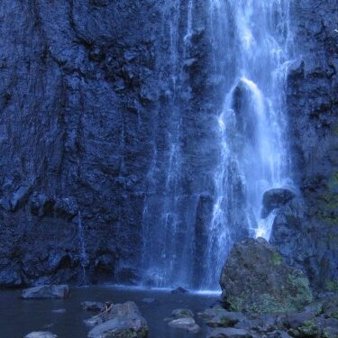 Waterfall cascading over dark rocky cliff.