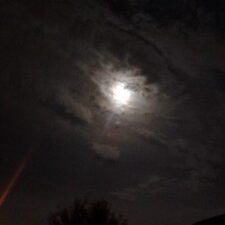Moonlight shining through cloudy night sky.