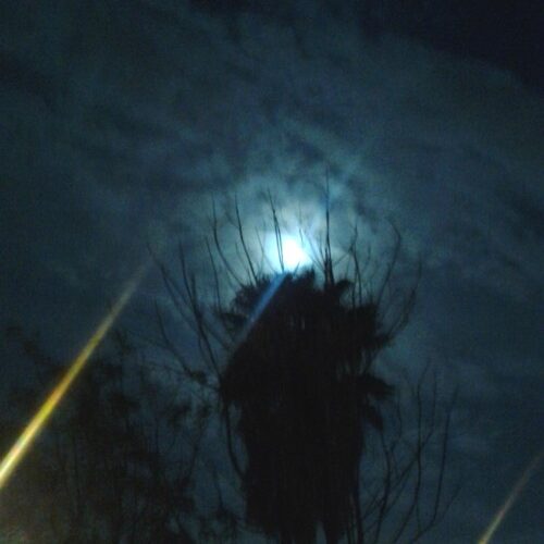 Moon shining through cloudy night sky.