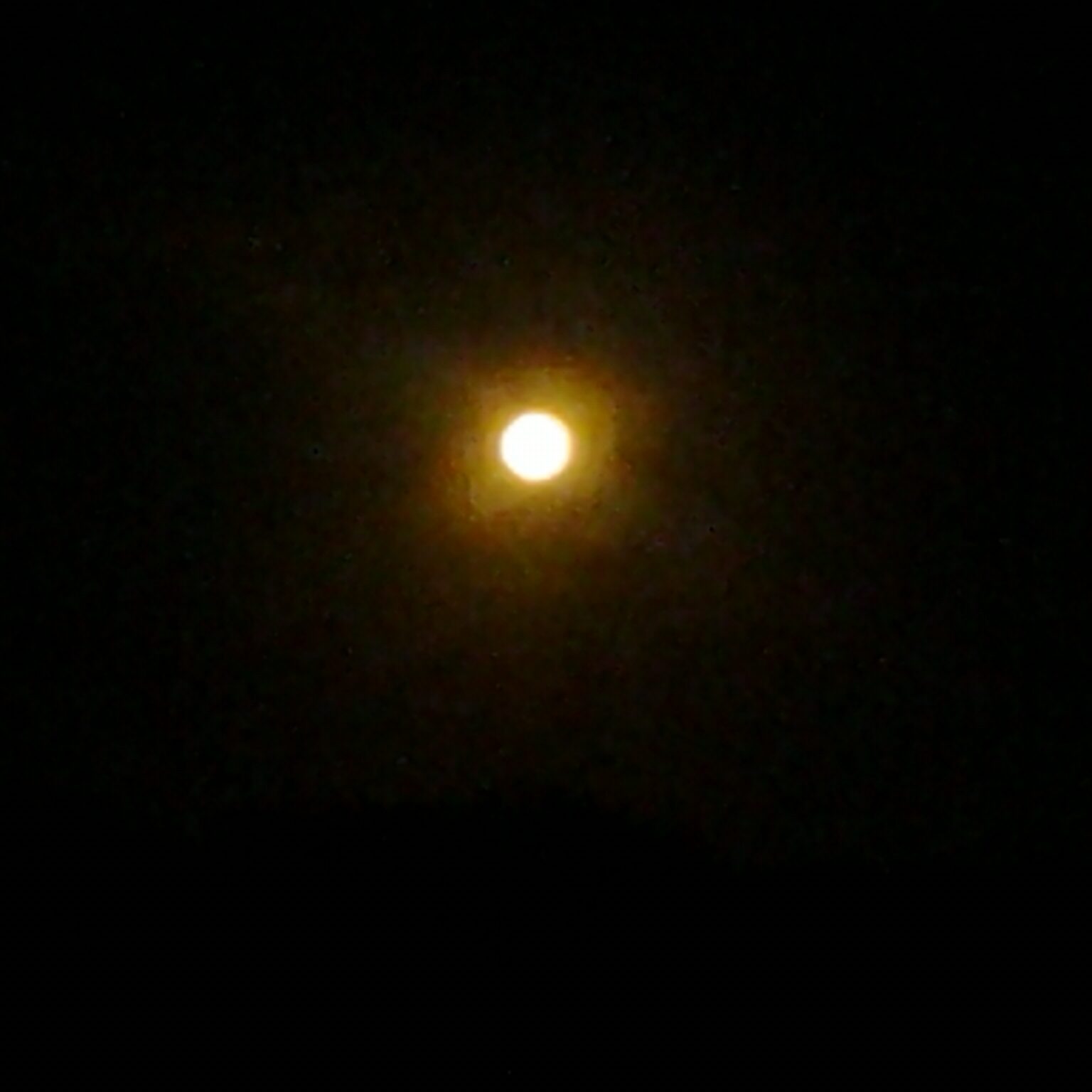 Bright full moon in dark night sky.