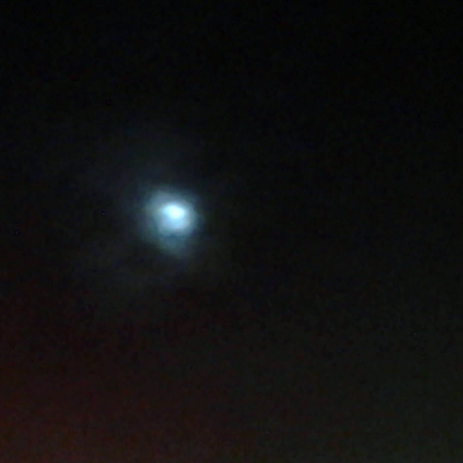 Faint moon in a dark, cloudy sky.