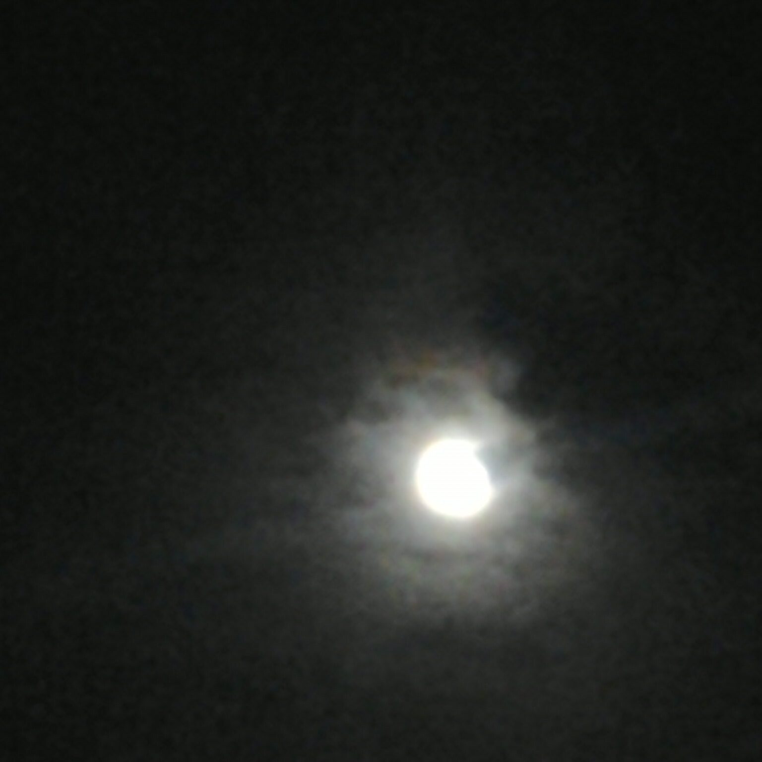 Bright moon surrounded by dark clouds.