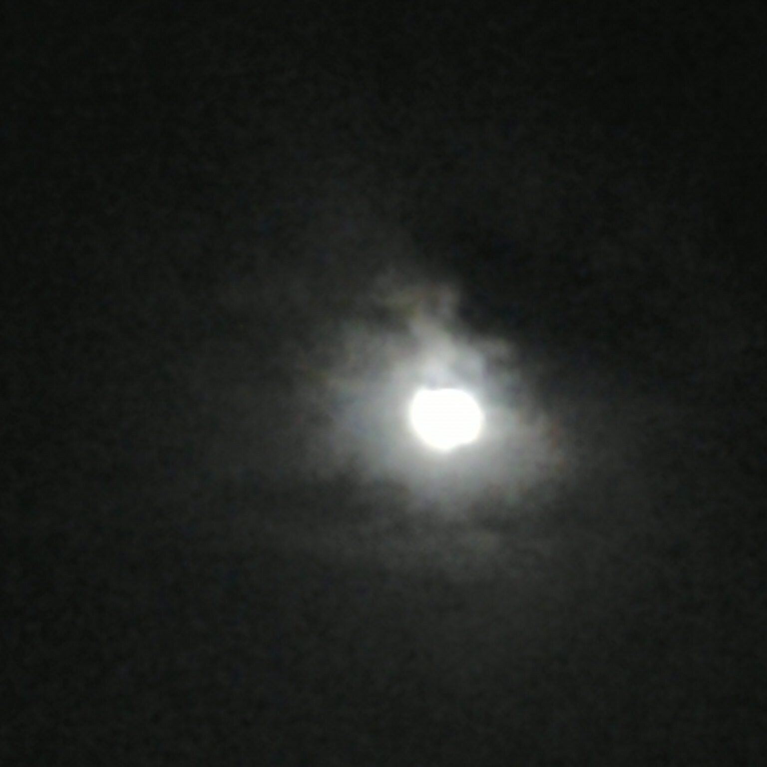 Blurry moon in a cloudy night sky.