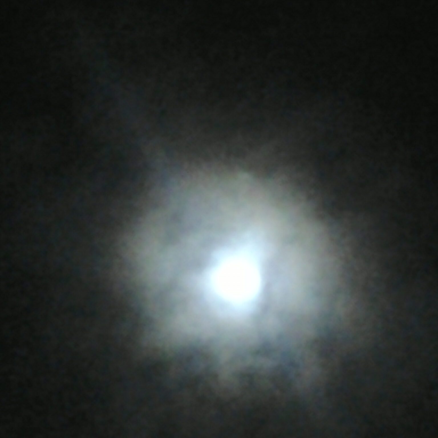 Bright full moon surrounded by cloudy haze.