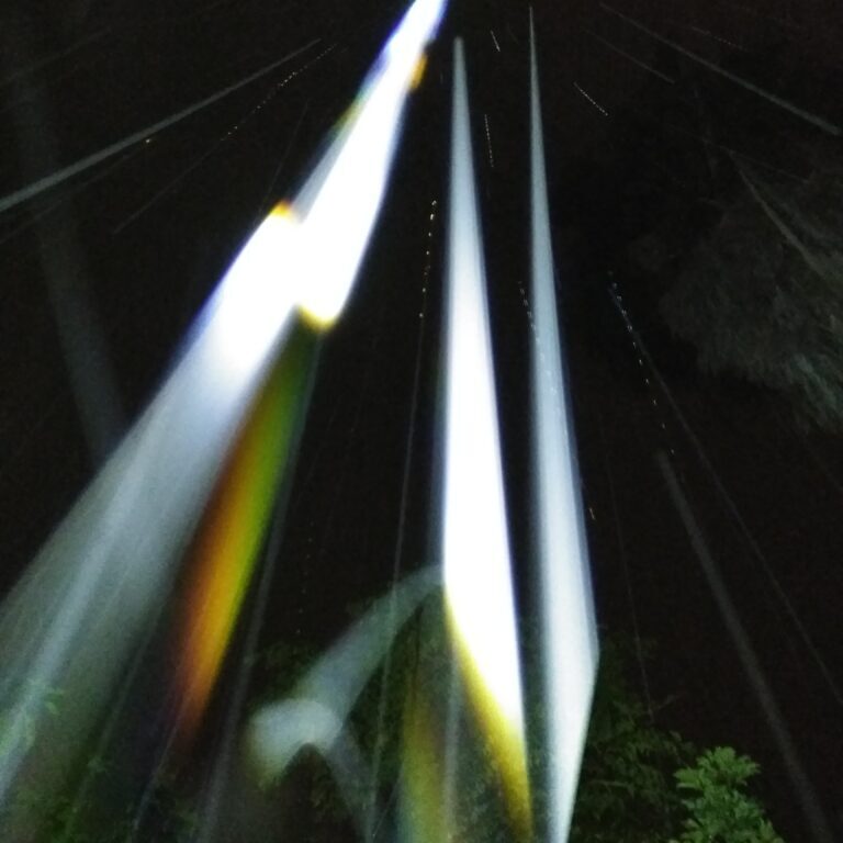 Colorful light beams against dark night sky.