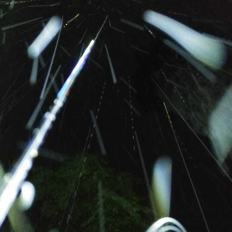 Nighttime rain with bright light streaks.