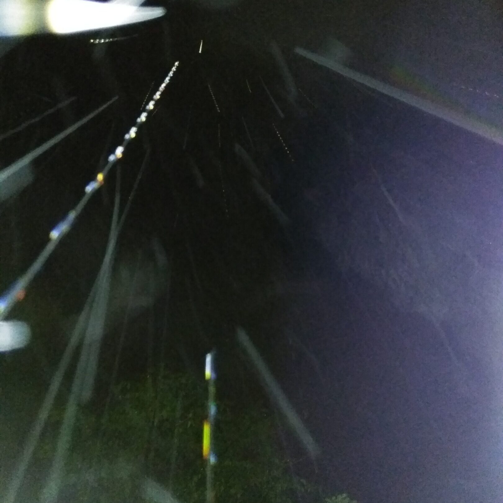 Nighttime rain with bright light streaks.