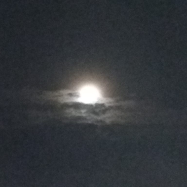 Bright moon shining through dark clouds.