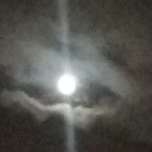 Bright moon surrounded by clouds at night.
