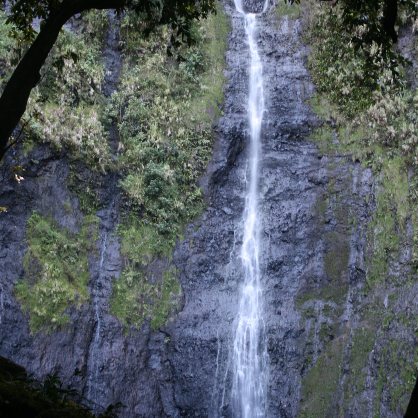 Tall waterfall cascading down rocky cliff.