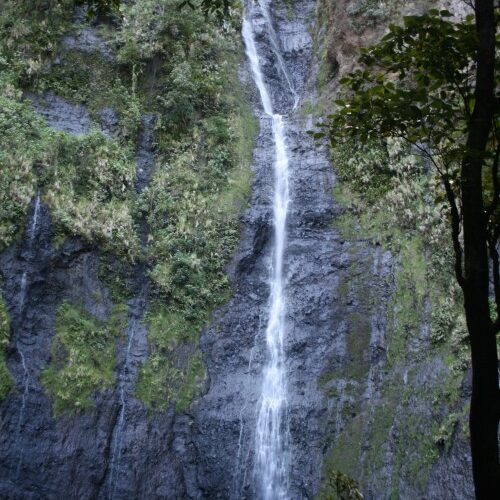 Tall waterfall cascading down rocky cliff.