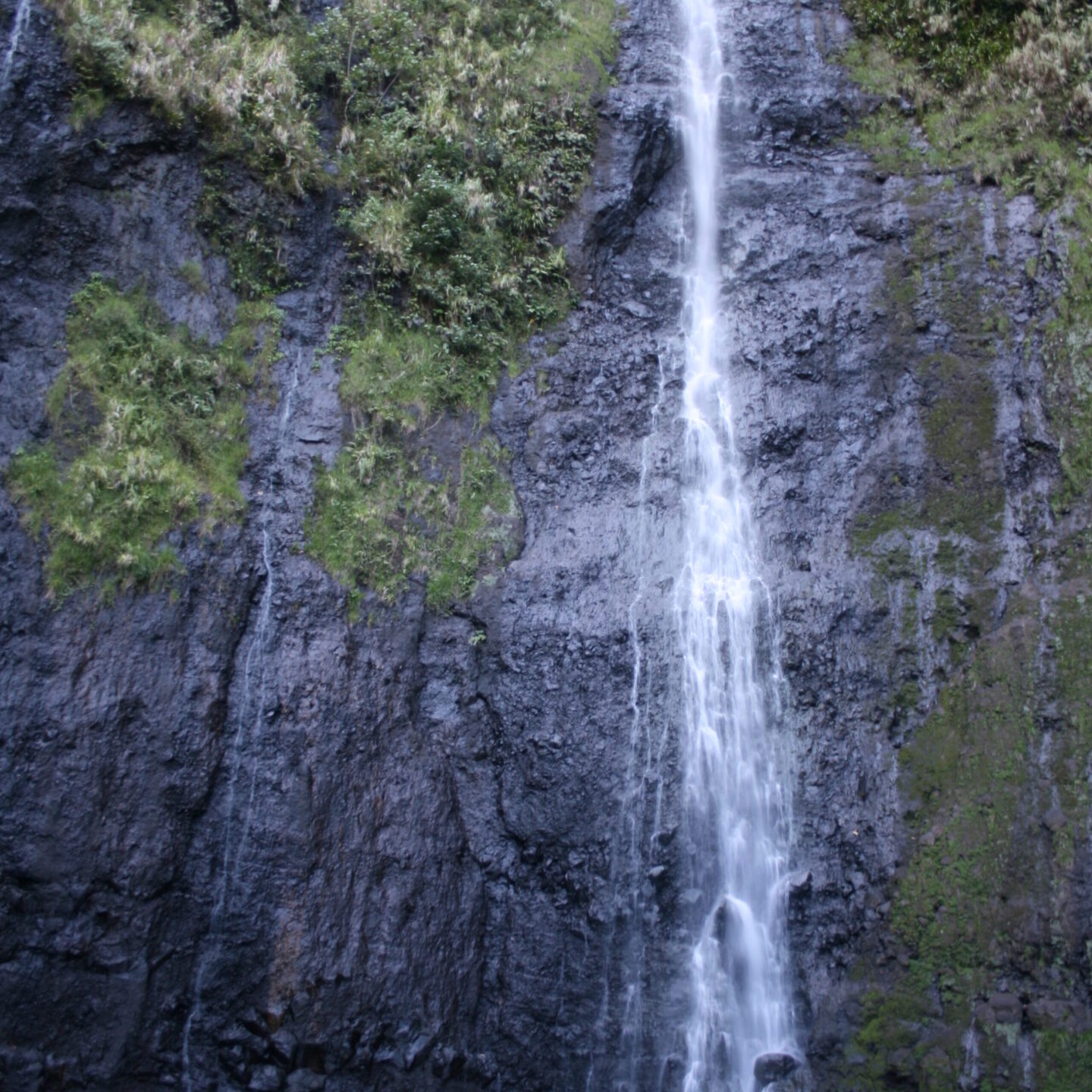 Tall waterfall cascading down rocky cliff.