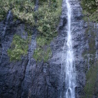 Tall waterfall cascading over rocky cliff.