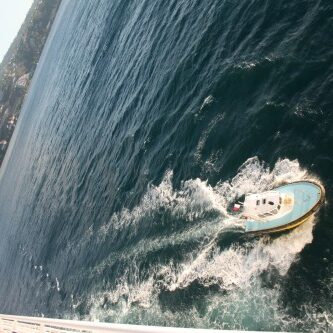 Boat navigating near a rocky coastline.