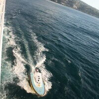 Boat speeding on ocean near coastline.