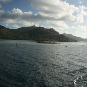 Mountainous island with cloudy sky and ocean.