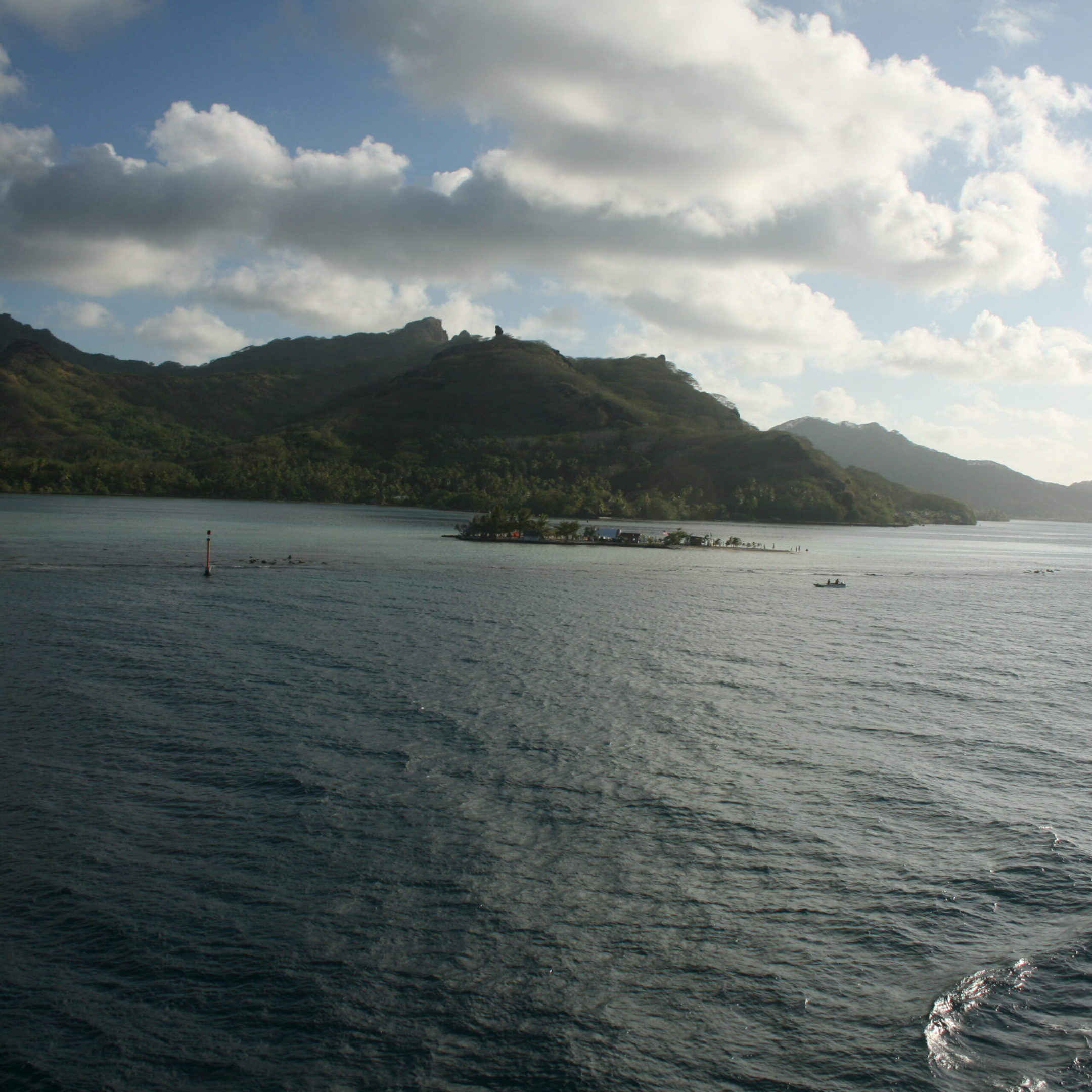 Tropical island with mountains and cloudy sky.