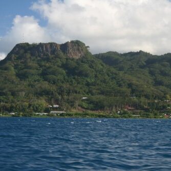 Mountain landscape with ocean and cloudy sky.