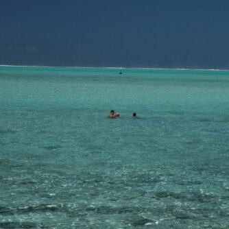Two people swimming in clear turquoise water.