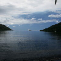Calm sea with distant boat and hills.