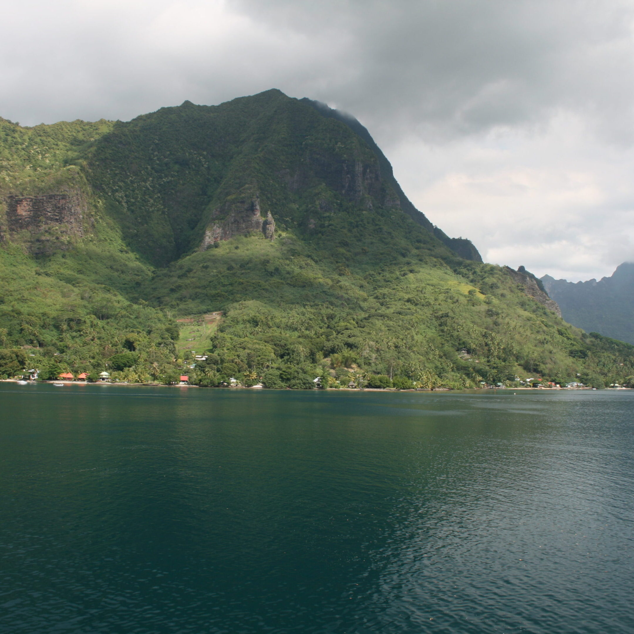 Mountain and lake under cloudy sky.