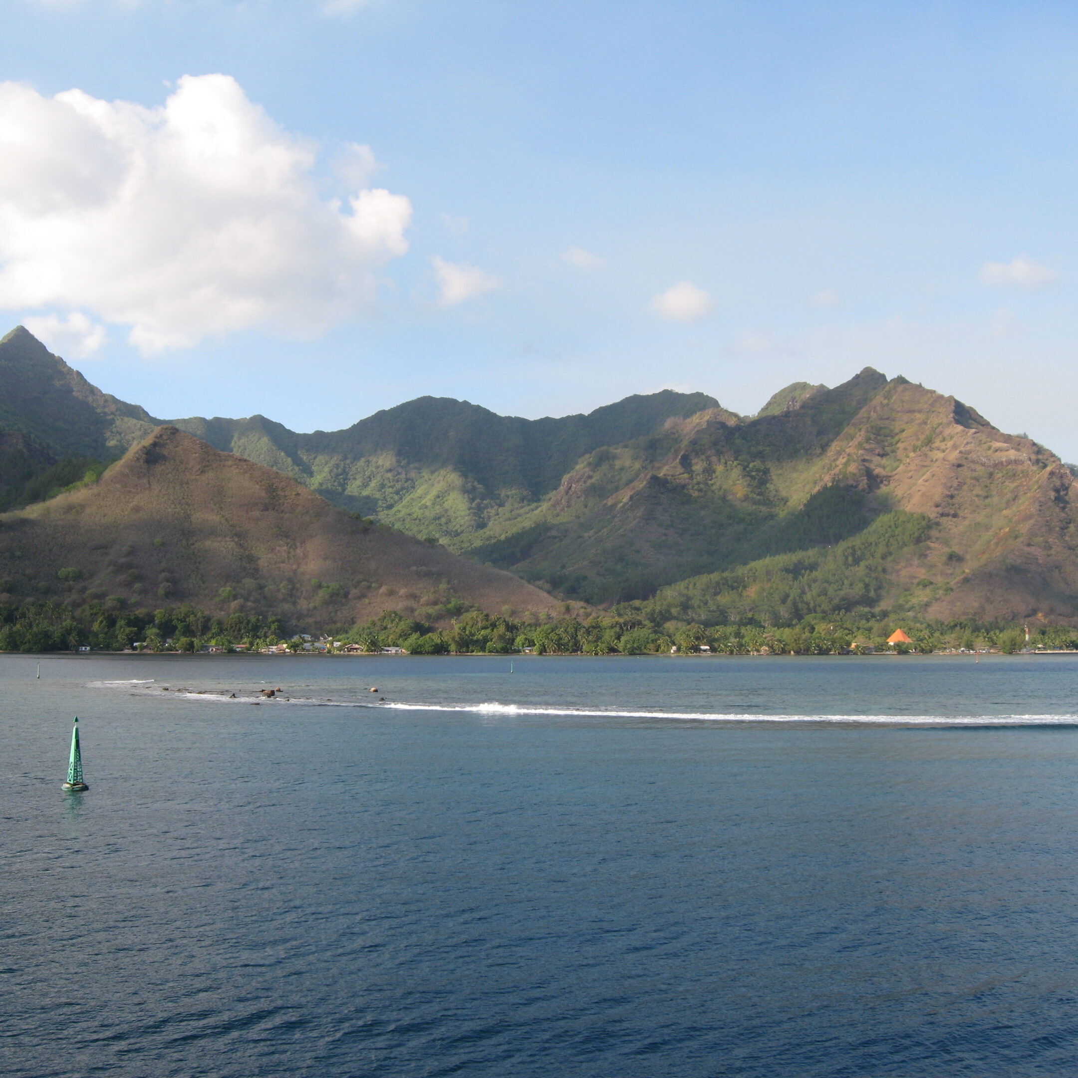 Mountainous coastline with blue sky and water.