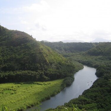 Lush valley with winding river and hills.