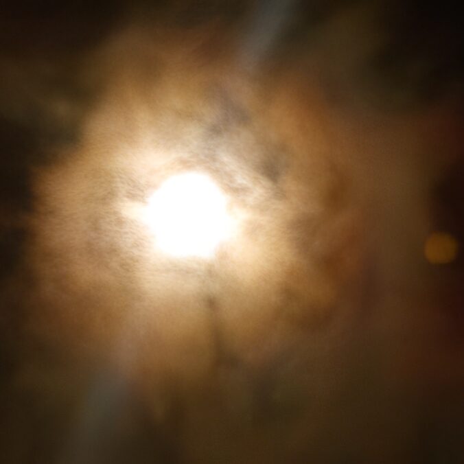 Bright sun obscured by swirling dark clouds.