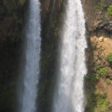 Two cascading waterfalls with surrounding greenery.